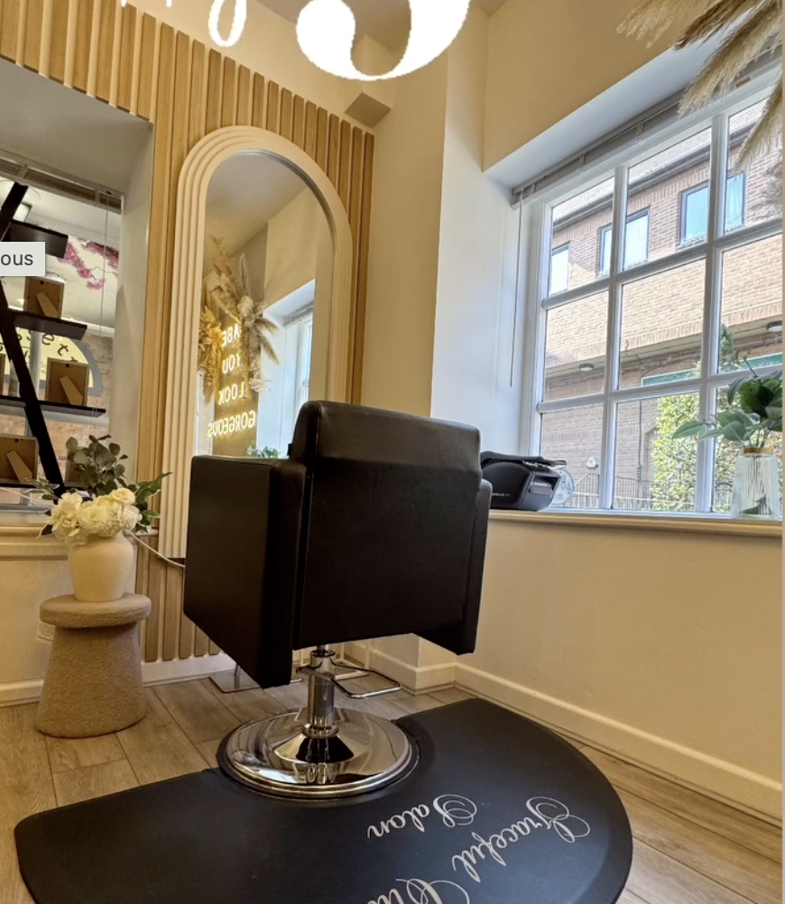 A styling chair beside the arched mirror and fluted wood panelling